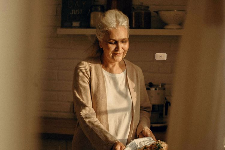 Een mevrouw die in de keuken bezig is waar je een sensor op de muur ziet.