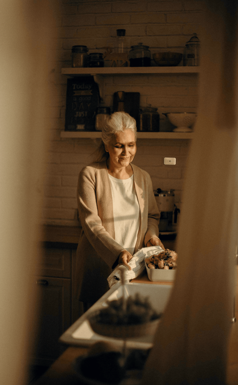 Een vrouw in haar keuken met een sensor op de muur.